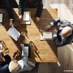 vue de haut de plusieurs personnes avec papier et crayon réunies autour d'une table