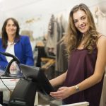 une jeune femme tient la caisse d'un magasin de vêtement