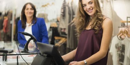 une jeune femme tient la caisse d'un magasin de vêtement