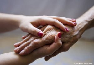 Deux mains jeunes avec vernis enserrent une main ridée