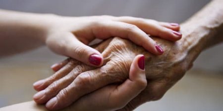 Deux mains jeunes avec vernis enserrent une main ridée