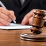 marteau de la justice et personne écrivant derrière