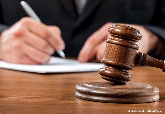 marteau de la justice et personne écrivant derrière