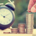 un réveil et une pile de pièces de monnaie