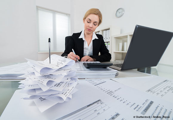 tickets et factures en premier plan, une femme avec une calculette et son