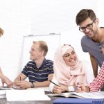 plusieurs personnes échangent à une table de travail dont une personne voilée