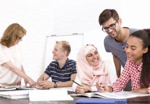 plusieurs personnes échangent à une table de travail dont une personne voilée