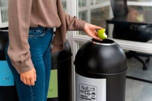 Employé de bureau utilisant un bac de tri design pour biodéchets, illustrant la valorisation des déchets organiques en entreprise.