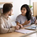 Manager expliquant une fiche de paie à une salariée lors d’un entretien avec documents et ordinateur portable